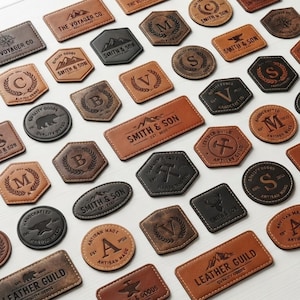 May include: A collection of assorted leather patches in tan, brown, and black colors. The patches feature various shapes including circles, rectangles, and hexagons, embossed with logos, monograms, and text such as Smith & Son and Leather Guild.