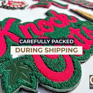 May include: Close-up of several embroidered patches with a green and red color scheme. The patches feature the word "Knockouts" in red, with a green textured background. The text "CAREFULLY PACKED DURING SHIPPING" is also visible.