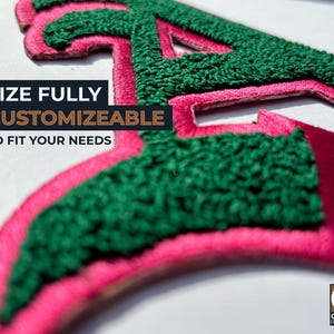 May include: Close-up of a custom patch with a green, textured letter "A" outlined in pink. The text "SIZE FULLY CUSTOMIZABLE TO FIT YOUR NEEDS" is displayed in a black and brown box. The Origin Patches logo is in the bottom right corner.
