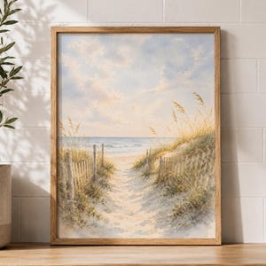 May include: A framed watercolor painting depicting a sandy beach path leading to the ocean. The scene features tall golden beach grass, a weathered wooden fence lining the walkway, and a soft blue sky with light clouds above the horizon.