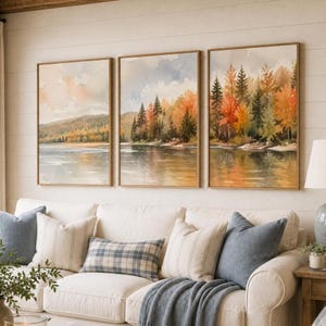May include: A triptych of three rectangular wall art prints featuring a watercolor landscape of a lake surrounded by autumn trees with orange, yellow, and green foliage under a soft sky, with reflections visible on the water surface.