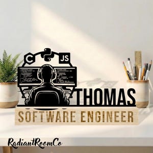 May include: A black and tan wooden desk sign featuring a silhouette of a person with headphones in front of a computer, with the name "THOMAS" and the words "SOFTWARE ENGINEER". The sign also includes the logos for C, Python, and JS.