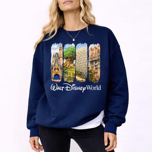Puede incluir: Sudadera azul marino con un dise&ntilde;o gr&aacute;fico colorido de los lugares emblem&aacute;ticos de Walt Disney World, como el Castillo de Cenicienta, el &Aacute;rbol de la Vida, Spaceship Earth y el Hollywood Tower Hotel. Las palabras "Walt Disney World" est&aacute;n impresas en blanco debajo.