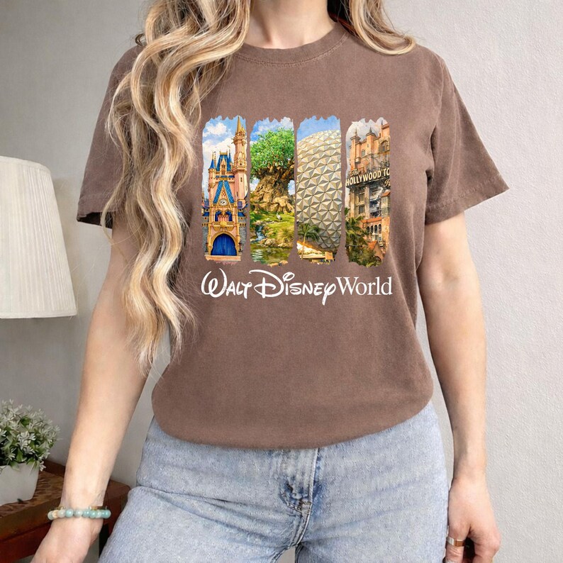 Puede incluir: Camiseta marr&oacute;n con un gr&aacute;fico colorido de los monumentos de Walt Disney World, incluyendo un castillo, el &Aacute;rbol de la Vida, Spaceship Earth y el Hollywood Tower Hotel. Las palabras "Walt Disney World" est&aacute;n impresas en blanco debajo.
