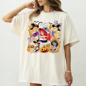 May include: Cream-colored t-shirt featuring a graphic of Disney princesses in Halloween costumes. The design includes the text "Spooky Princess Gathering" and "Happy Halloween", along with pumpkins and bats.