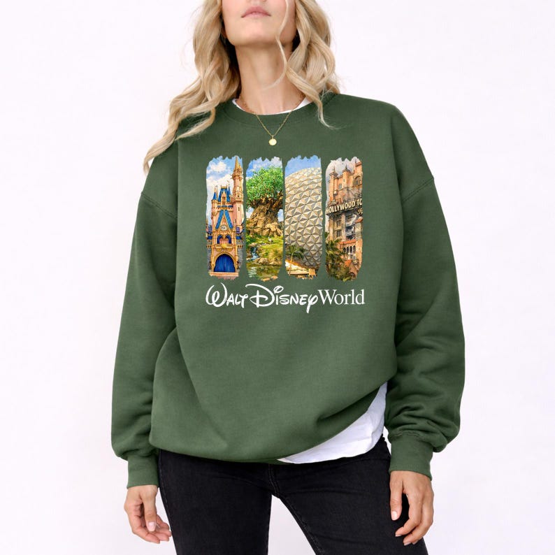 Puede incluir: Sudadera verde oscuro con un gr&aacute;fico colorido de los lugares emblem&aacute;ticos de Walt Disney World. El dise&ntilde;o incluye el castillo de Cenicienta, el &Aacute;rbol de la Vida, Spaceship Earth y el Hollywood Tower Hotel. Las palabras "Walt Disney World" est&aacute;n impresas en blanco.