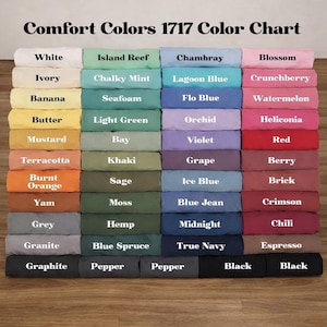 May include: A color chart displaying a variety of fabric colors from Comfort Colors 1717. The chart includes shades like white, ivory, banana, mustard, terracotta, burnt orange, yam, grey, granite, graphite, island reef, chalky mint, seafoam, light green, bay, khaki, sage, moss, hemp, blue spruce, pepper, chambray, lagoon blue, flo blue, orchid, violet, grape, ice blue, blue jean, midnight, true navy, blossom, crunchberry, watermelon, heliconia, red, berry, brick, crimson, chili, espresso, and black.