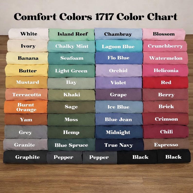 May include: A color chart displaying a variety of fabric colors from Comfort Colors 1717. The chart includes shades like white, ivory, banana, mustard, terracotta, burnt orange, yam, grey, granite, graphite, island reef, chalky mint, seafoam, light green, bay, khaki, sage, moss, hemp, blue spruce, pepper, chambray, lagoon blue, flo blue, orchid, violet, grape, ice blue, blue jean, midnight, true navy, blossom, crunchberry, watermelon, heliconia, red, berry, brick, crimson, chili, espresso, and black.