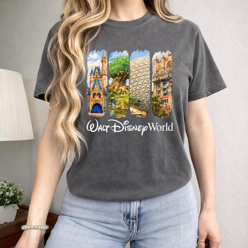 Puede incluir: Camiseta gris oscuro con un gr&aacute;fico colorido de los lugares emblem&aacute;ticos de Walt Disney World. El dise&ntilde;o incluye im&aacute;genes del castillo de Cenicienta, el &Aacute;rbol de la Vida, Spaceship Earth y el Hollywood Tower Hotel, con "Walt Disney World" escrito debajo.