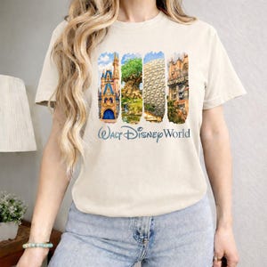 Puede incluir: Camiseta beige con cuatro im&aacute;genes verticales de los lugares emblem&aacute;ticos de Disney World: un castillo, el &Aacute;rbol de la Vida, Spaceship Earth y el Hollywood Tower Hotel. Las palabras "Walt Disney World" est&aacute;n impresas en azul debajo.