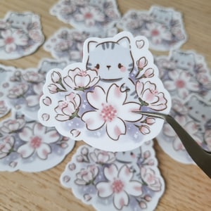 Eine graue Katze mit Sakura Blume, glänzende Sticker und laminierter, wasserfester Sticker.