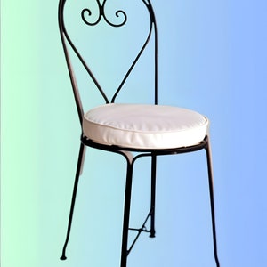 May include: A black metal chair with a heart-shaped back and a white cushion. The chair has a simple design and is perfect for a patio or garden.
