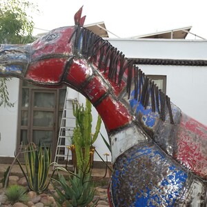 May include: A large metal sculpture of a horse's head, painted in red, white, and blue. The horse's mane is made of metal chains.