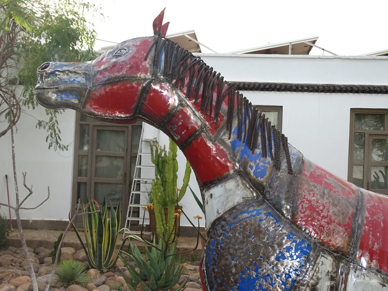 May include: A large metal sculpture of a horse's head, painted in red, white, and blue. The horse's mane is made of metal chains.