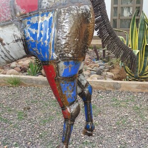 May include: A metal sculpture of a horse with a patchwork design of red, blue, and white. The horse's tail is made of metal chains.