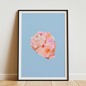 May include: A framed wall art print featuring a painterly illustration of a pink and orange seashell centered on a solid light blue background. The artwork is enclosed in a thin black rectangular frame, displaying a textured, brushstroke style.