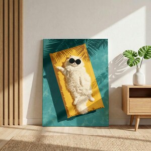 May include: A rectangular wall art print featuring a fluffy white cat wearing round black sunglasses, lying on a bright yellow rectangular mat. The background is a teal blue surface with dark palm leaf shadows cast across the entire scene.