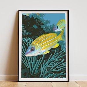 May include: A framed art print featuring two yellow and blue striped fish swimming near teal coral. The fish have blue and yellow fins and are set against a dark green background. The artwork is framed in a black frame.