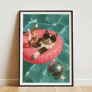 May include: A framed wall art print featuring a brown and white cat wearing black sunglasses, floating in a bright pink inflatable ring in turquoise pool water. The cat holds a glass of wine, and a silver disco ball floats nearby in the water.