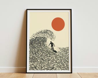 May include: A framed wall art print featuring a black silhouette of a surfer riding a large, textured wave. The background is a light cream color with a solid, burnt orange circle representing the sun positioned in the upper right corner.