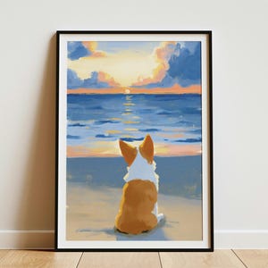 May include: A framed art print featuring a painting of a brown and white Corgi dog sitting on a sandy beach, facing a blue ocean and a sunset sky with orange and yellow clouds. The artwork is enclosed in a simple black rectangular frame.