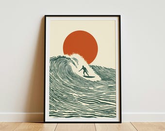 May include: Framed art print featuring a surfer riding a wave under a large orange sun. The artwork has a minimalist style with a cream-colored background and a black frame. The wave and surfer are in shades of green.