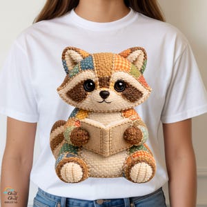 May include: A white t-shirt with a detailed illustration of a patchwork raccoon reading a book. The raccoon is crafted from various fabrics in brown, orange, blue, and green. The image includes the text "Chill Digital" in the bottom left corner. The design is vibrant and whimsical.