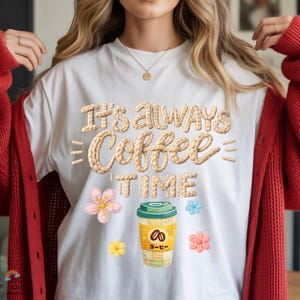 May include: White t-shirt with the text "It's Always Coffee Time" in a beige, textured font. The shirt features a coffee cup graphic and floral accents in pink, yellow, and blue. A red cardigan is worn over the shirt.