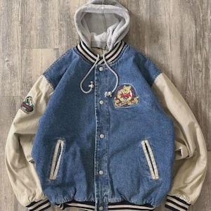 Pode incluir: Casaco de ganga azul com capuz cinzento e mangas bege. O casaco apresenta um patch do Ursinho Pooh e dois bolsos frontais. Os punhos e a bainha têm detalhes listrados em preto e branco.