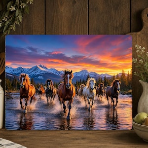 May include: A rectangular wall art print featuring a herd of horses galloping through shallow water. The scene includes snow-capped mountains and a forest under a vibrant sunset sky with orange, pink, and purple clouds reflecting in the water.