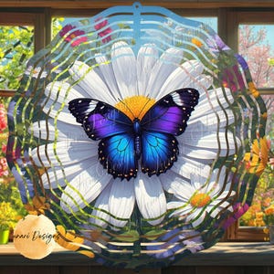 May include: A decorative metal wind spinner featuring a large white daisy with a yellow center and a vibrant blue and purple butterfly. The spinner has a wavy, layered design and is set against a blurred floral background.