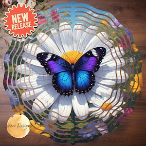 Puede incluir: Un spinner de jardín decorativo de metal con una vibrante mariposa azul y púrpura sobre una margarita blanca. El diseño incluye un efecto ondulado y en capas con acentos florales y el texto "NEW RELEASE".