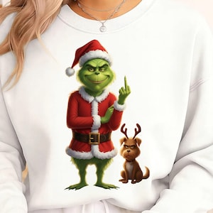 May include: White sweatshirt featuring a Grinch character in a Santa suit, giving the middle finger. The Grinch is green with a red Santa hat and suit. A brown dog with antlers is next to him.