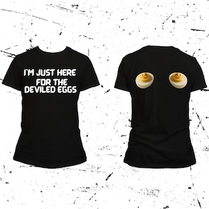 May include: Black t-shirt with the text "I'M JUST HERE FOR THE DEVILED EGGS" in white. The back of the shirt features two deviled egg graphics. The shirt is a casual, humorous apparel item.