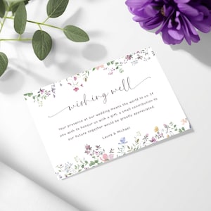 Puede incluir: Tarjeta blanca de boda con detalles florales. La tarjeta presenta las palabras "wishing well" en escritura elegante, junto con un mensaje sobre regalos. La tarjeta está decorada con flores de acuarela.