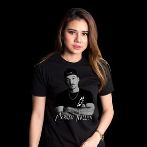 K&ouml;nnte beinhalten: Schwarzes T-Shirt mit einem Schwarz-Wei&szlig;-Bild von Morgan Wallen und seinem Namen darunter. Das Bild zeigt Wallen mit einer schwarzen Kappe und einer Halskette. Der Hintergrund ist einfarbig schwarz.