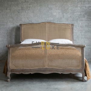 May include: A wooden bed frame with a woven cane headboard and footboard. The bed has a distressed, grey finish and is styled with white pillows and a tan bed skirt. The bed frame is a classic design.