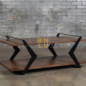 May include: A two-tiered coffee table with a dark wood finish and black metal supports. The table has a rectangular shape and a modern design. The brand name "FURN LUXE" is visible in the bottom right corner.