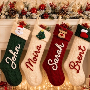 May include: Four cable-knit Christmas stockings hanging in a row. The first is dark green with a white cuff and the name John. The second is cream with a cream cuff and the name Moira. The third is red with a red cuff and the name Sarah. The fourth is cream with a dark green cuff and the name Brent.
