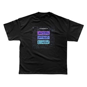 以下が含まれることがあります： 黒いTシャツ。ネオンのグラフィックデザインが特徴で、紫、青、ティールの3つの水平な長方形があります。「TWO DOOR CINEMA CLUB」の文字が長方形の上にあります。このシャツは柔らかい素材で作られています。