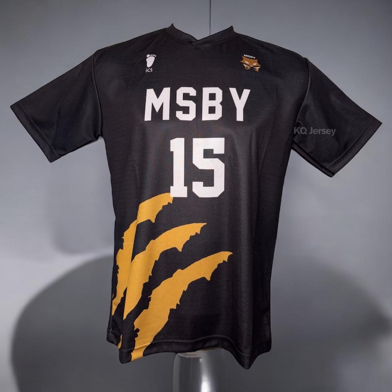 May include: Black athletic jersey with the text "MSBY" and the number "15" in white. The jersey has a claw mark design in gold on the lower left side. The jersey also has the text "KQ Jersey" on the right sleeve.