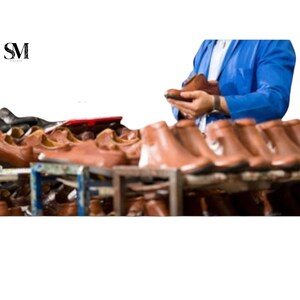 May include: A selection of brown leather shoes on wooden shelving. A person in a blue jacket is holding a brown leather shoe. The shoes appear new, indicating a focus on footwear, possibly for sale.