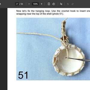 Puede incluir: Un colgante de concha de macram&eacute; con un ganchillo insertado en la concha. La concha es blanca con un borde de macram&eacute; beige y un lazo para colgar. El n&uacute;mero 51 est&aacute; en la esquina inferior izquierda.