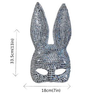 May include: A silver bunny mask covered in sparkling rhinestones. The mask measures 13 inches (33.5cm) in height and 7 inches (18cm) in width. The mask has eye openings and long, upright ears, perfect for a costume or party.