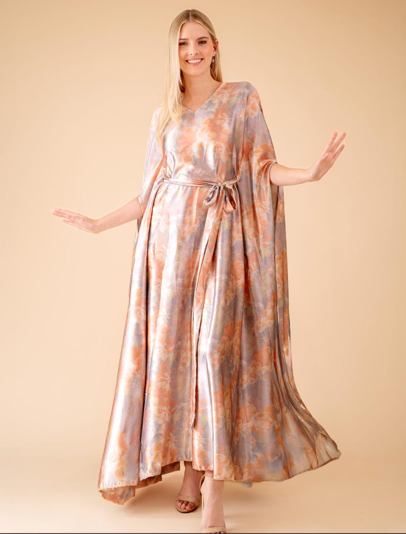 May include: A long, flowing, pink and purple tie-dye maxi dress with a V-neck and a sash tie at the waist.