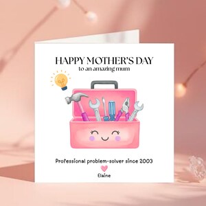 May include: A Mother's Day card featuring a pink toolbox illustration. The card's text reads "Happy Mother's Day to an amazing mum" and "Professional problem-solver since 2003". The card is personalized with the name "Elaine".