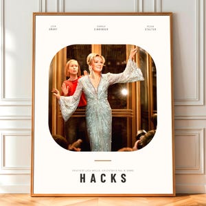 Puede incluir: Un póster enmarcado con la palabra "HACKS" en letras blancas. La imagen central del póster muestra a dos mujeres en un entorno interior. La parte superior del póster enumera los nombres "JEAN SMART", "HANNAH EINBINDER" y "MEGAN STALTER".