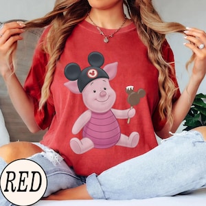 May include: Red t-shirt featuring a cartoon pig wearing a black Mickey Mouse hat and holding a Mickey Mouse-shaped ice cream bar. The word "RED" is printed in a white circle at the bottom of the image.