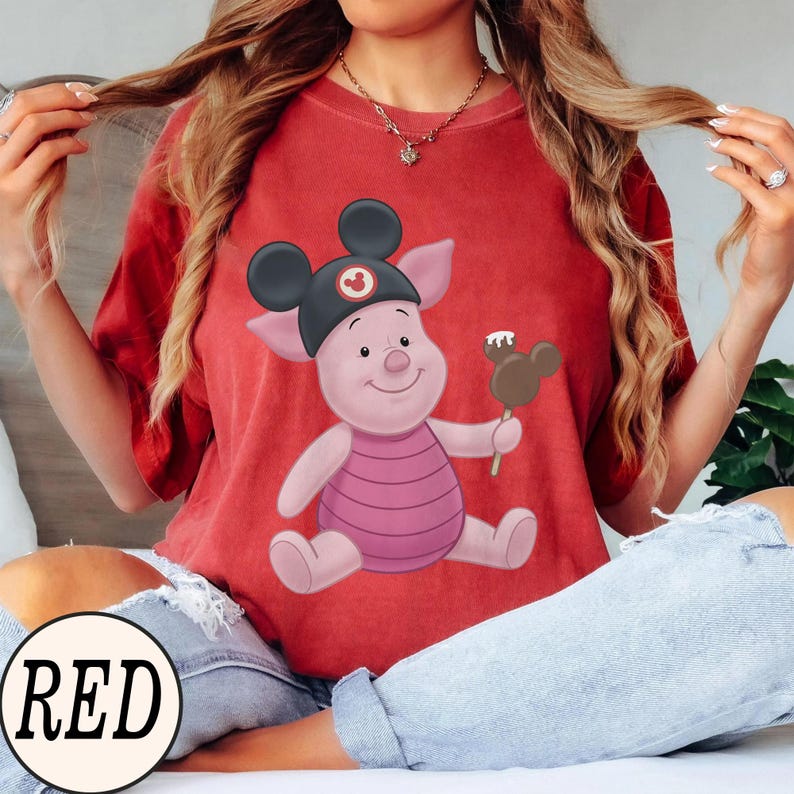 May include: Red t-shirt featuring a cartoon pig wearing a black Mickey Mouse hat and holding a Mickey Mouse-shaped ice cream bar. The word "RED" is printed in a white circle at the bottom of the image.
