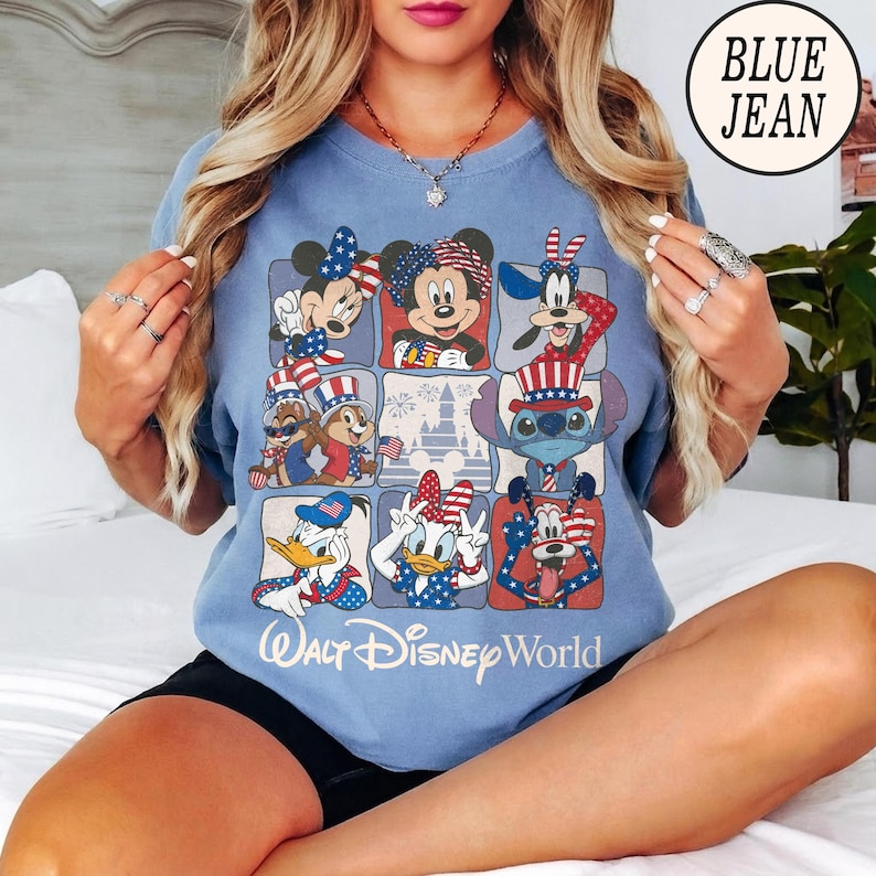 May include: Light blue t-shirt featuring a grid of Disney characters in patriotic attire. Mickey and Minnie Mouse, Goofy, Chip and Dale, Stitch, Donald and Daisy Duck, and Goofy are depicted. The text "Walt Disney World" is printed below the grid.